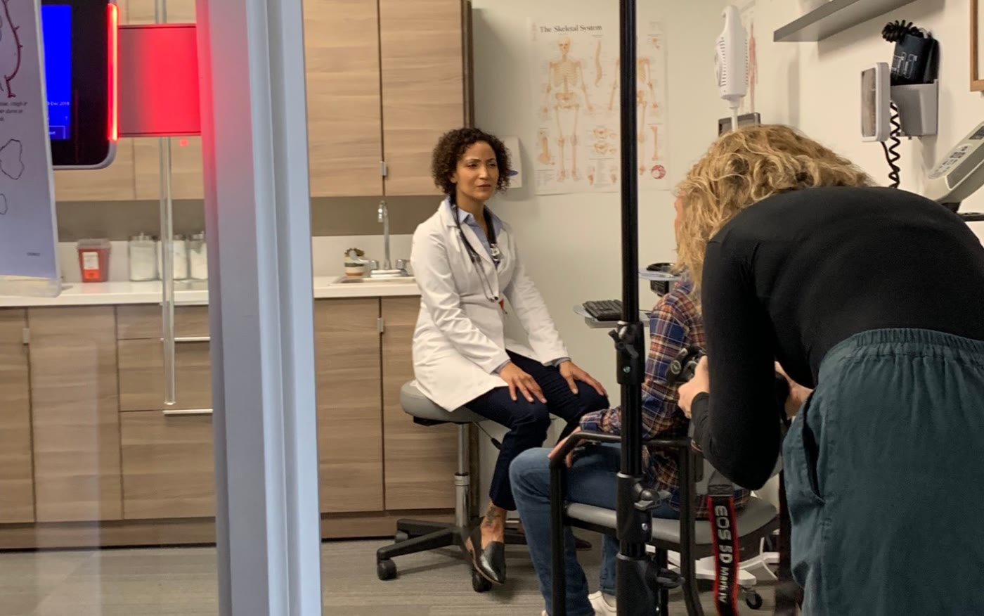 Behind the scenes: a photographer shooting a doctor and patient in an exam room under studio lights