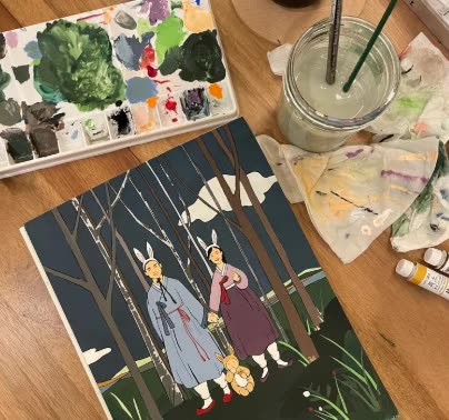 A painting in progress next to a watercolor palette